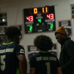 Player 5, 1, and their coach are thinking of the next move as they have 11 seconds left in their basketball game.